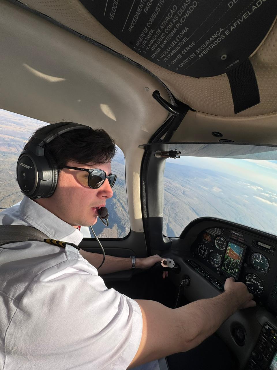 Eduardo Nunes Pereira pilotando, com fones Bose e uniforme, no comando de uma aeronave em voo IFR